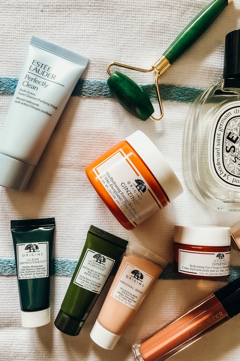 Top view of skincare products and jade roller on a textured surface, showcasing various brands.